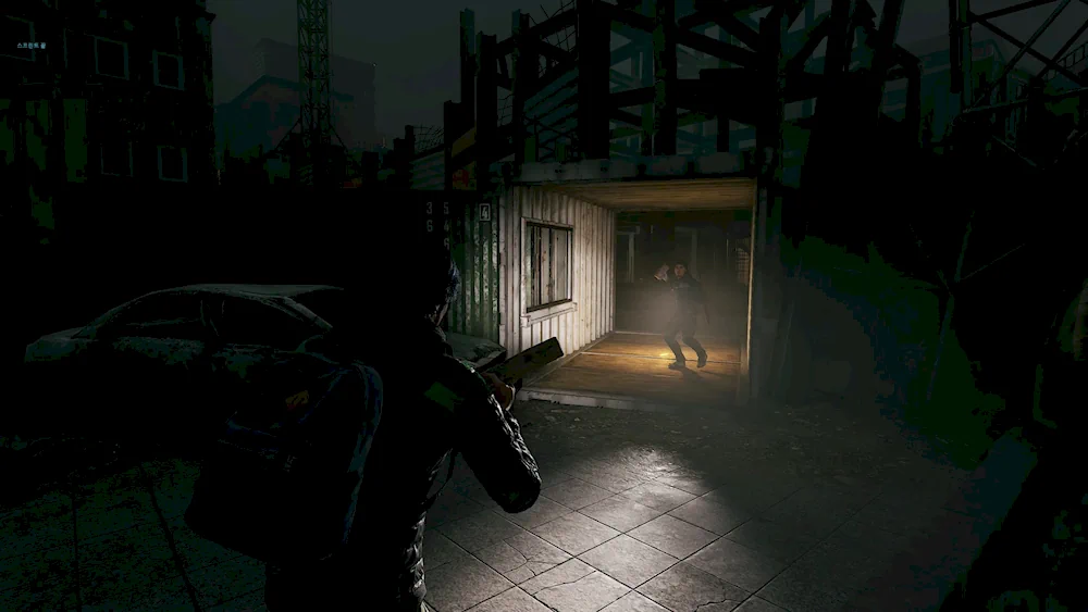 Игрок от третьего лица в темном заброшенном месте направляет фонарик на другого выжившего в открытом грузовом контейнере.